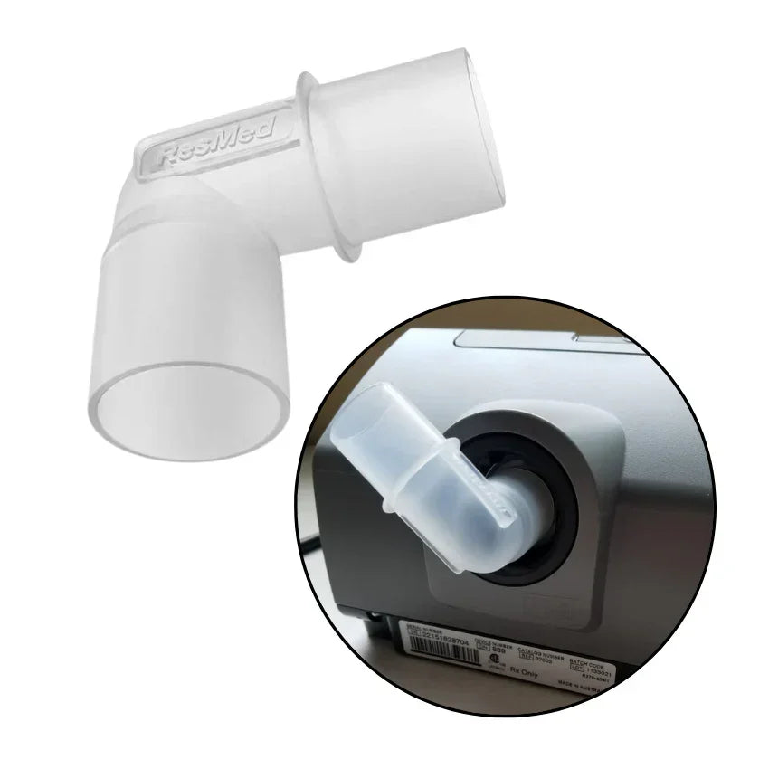CPAP hose elbow connector for sleep apnea machine, clear plastic, shown attached to device