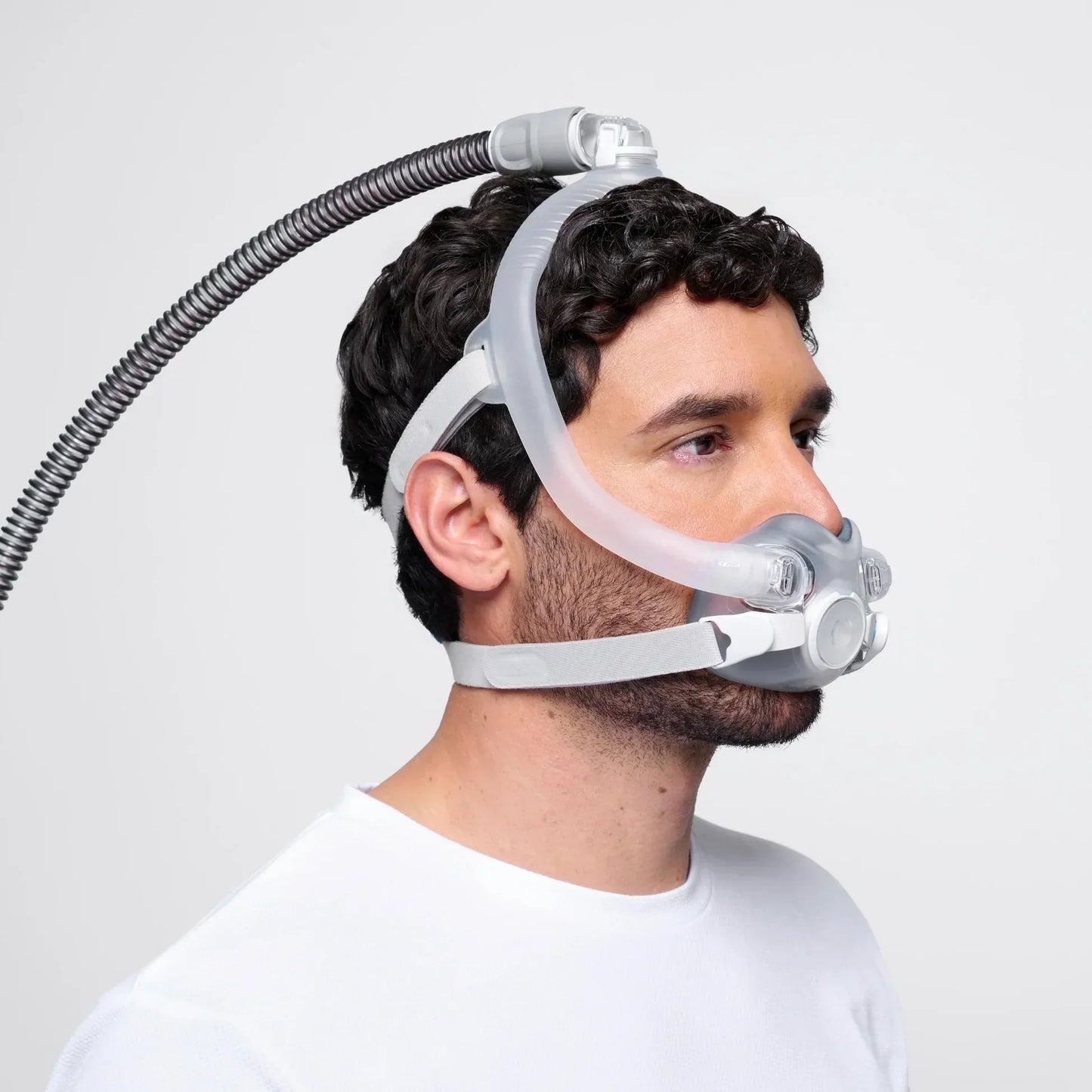 Man wearing CPAP nasal mask with headgear and hose for sleep apnea therapy