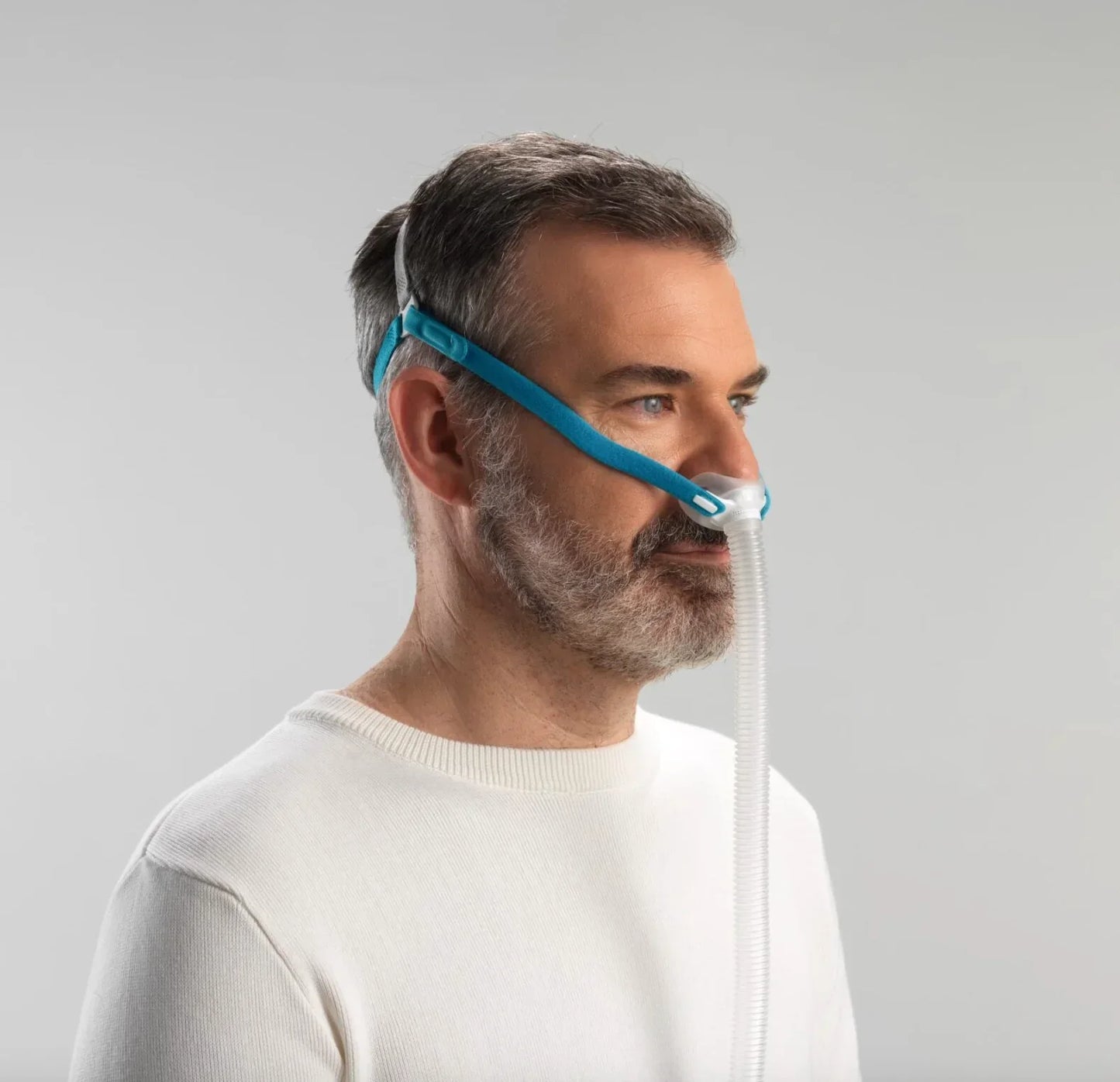 Man wearing lightweight nasal CPAP mask with headgear and hose for sleep therapy
