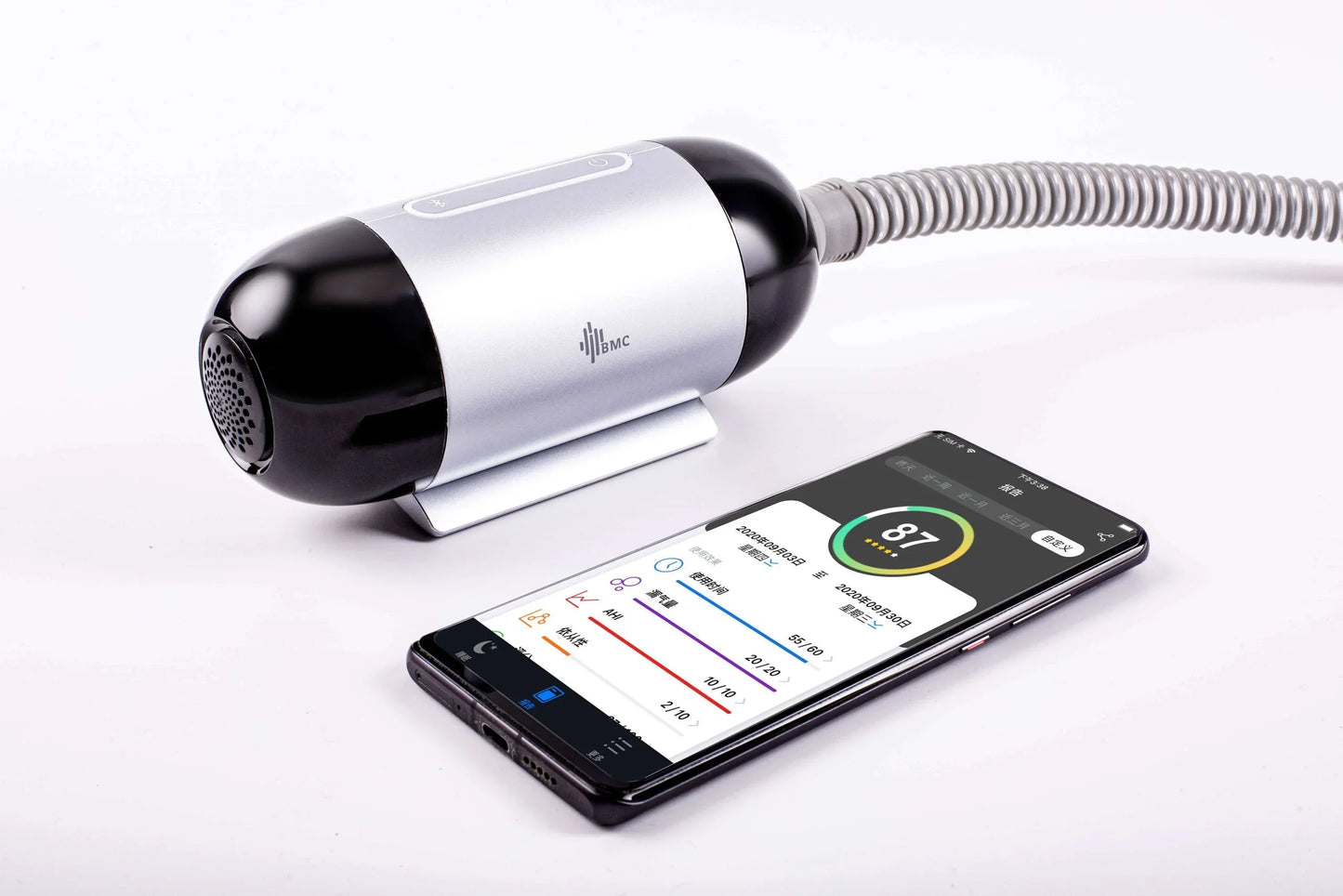 Compact CPAP machine with connected hose beside smartphone app displaying sleep data