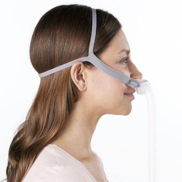 Woman wearing nasal CPAP mask with headgear for sleep apnea therapy