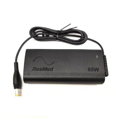 ResMed 65W CPAP machine power supply with attached cable on white background
