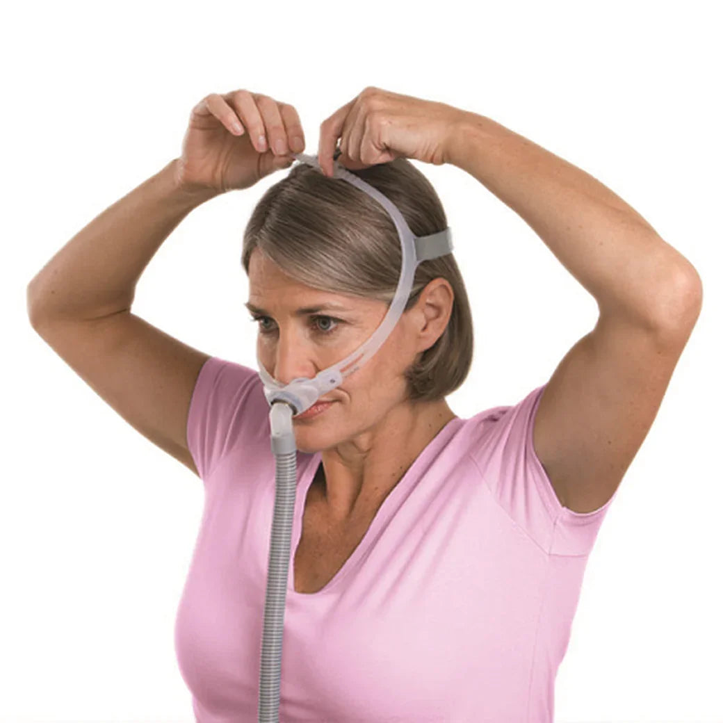 Woman adjusting nasal CPAP mask with headgear for sleep apnea therapy