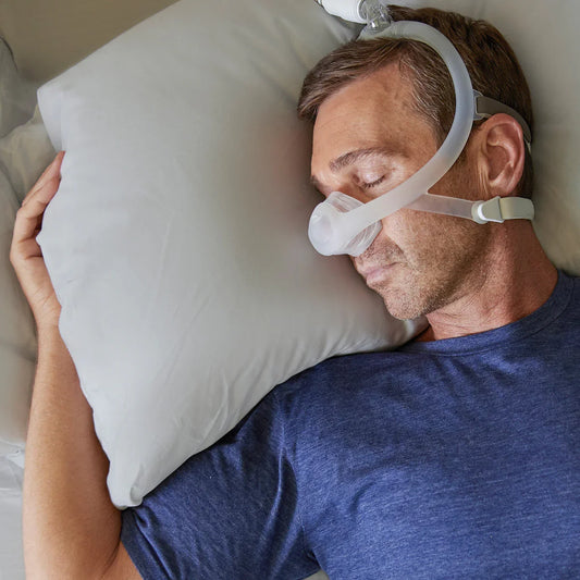 Side sleeper wearing a nasal CPAP mask lying on a pillow, sleep apnea therapy device