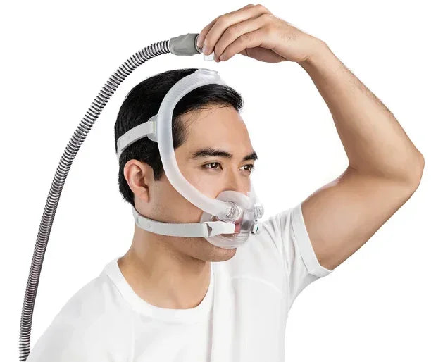 Man wearing CPAP nasal mask with headgear and hose for sleep apnea therapy