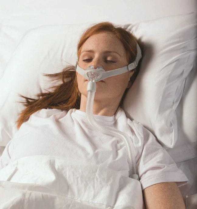 Woman sleeping with CPAP nasal mask for sleep apnea therapy in bed