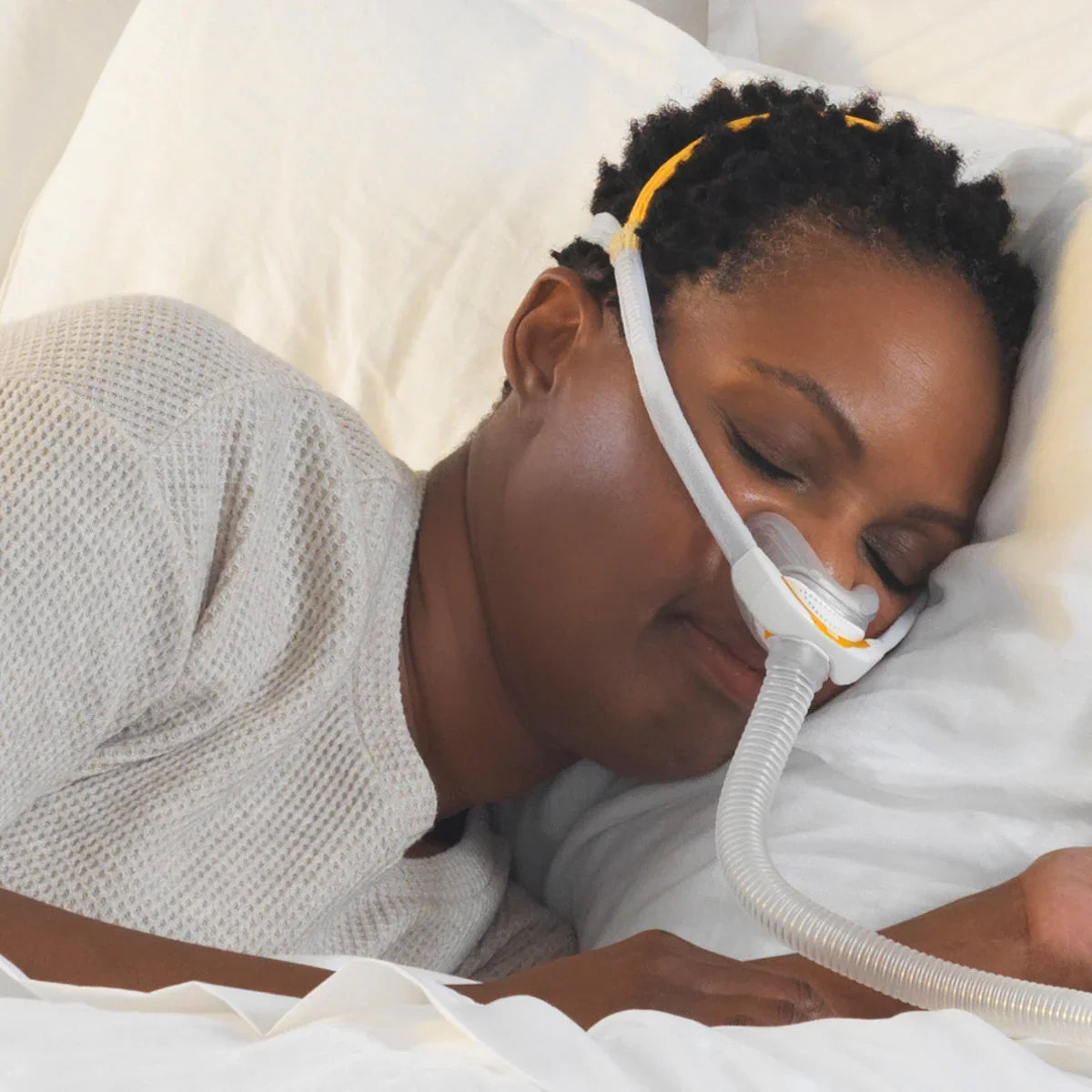Woman sleeping on her side wearing a nasal CPAP mask for sleep apnea therapy