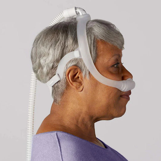 Woman wearing DreamWear nasal pillows CPAP mask for sleep apnea support, side view