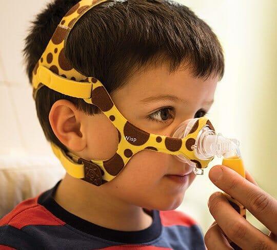 Child wearing giraffe-print CPAP nasal mask for sleep apnea therapy