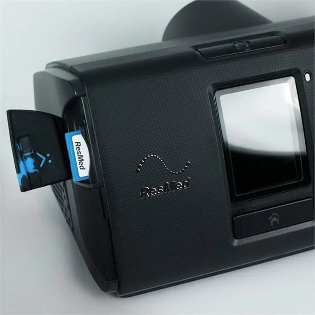 A close-up of a black ResMed CPAP Machine showing the side panel open to reveal a blue-and-white ResMed brand card or module inserted into a side port.